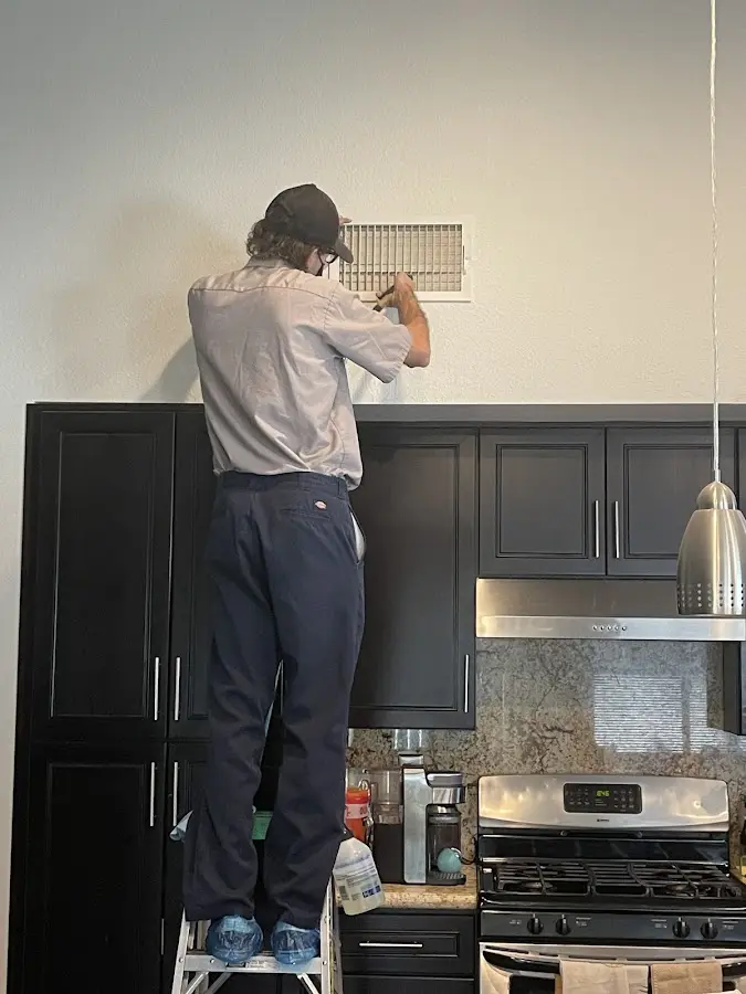 Technician inspecting an air vent during HVAC service in Plover